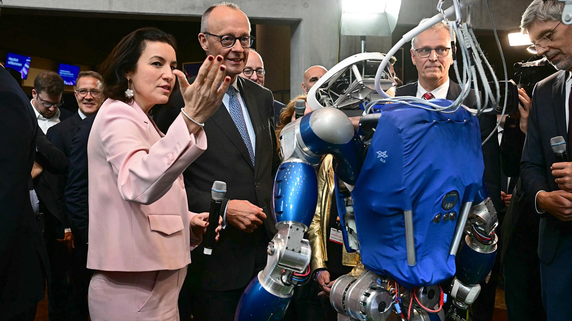 Dorothee Bär und Friedrich Merz betrachten den humanoiden Laufroboter TORO. | dpa