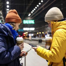Zwei Frauen schauen an einem Gleis am HBF Köln auf ihre Handys