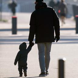 Ein Mann hält ein kleines Kind an der Hand.