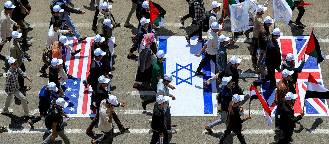 Studenten laufen auf dem Campus der Universität Sanaa in der von den Huthi kontrollierten jemenitischen Hauptstadt über Darstellungen der Flaggen der USA, Israels und Großbritanniens.