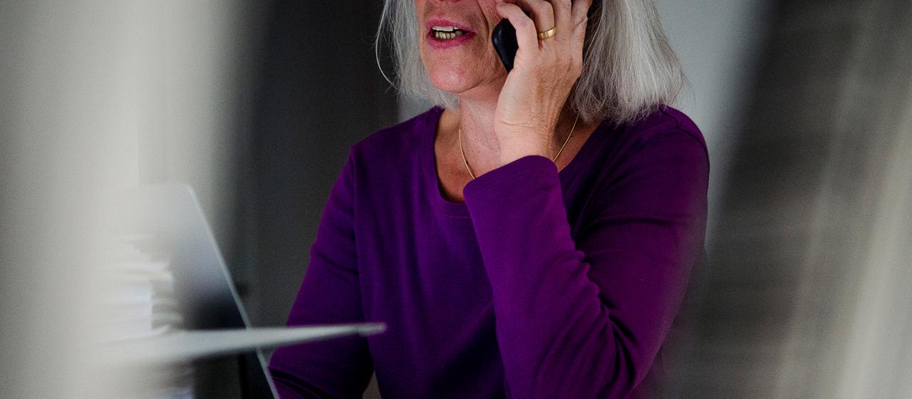 Eine Frau sitzt an einem Tisch und telefoniert.