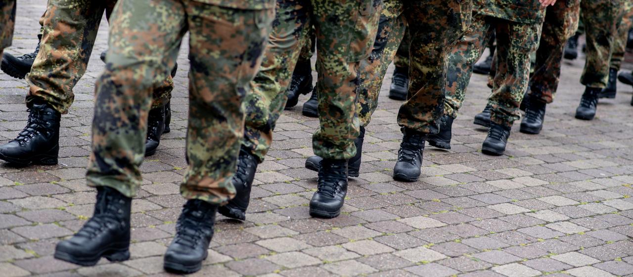 Reservistinnen und Reservisten marschieren in einer Reihe in Uniform.