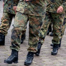 Reservistinnen und Reservisten marschieren in einer Reihe in Uniform.