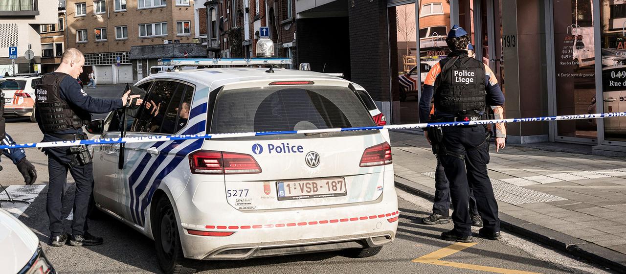 Polizisten stehen an Absperrungen und sichern ein Gebiet in Lüttich.