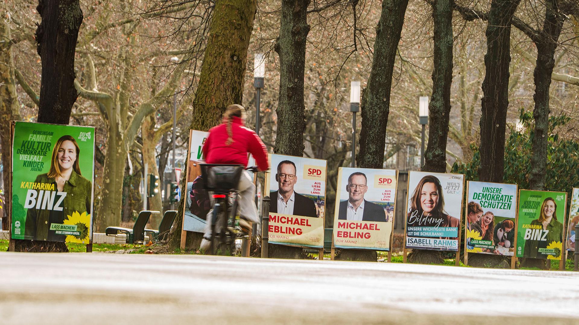 Eine Frau fährt mit einem Fahrrad an Wahlplakaten in Mainz vorbei. | Andreas Arnold/dpa