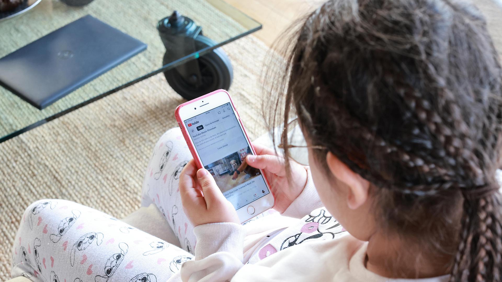 Ein Mädchen guckt Youtube-Videos auf einem Smartphone. | picture alliance / Hans Lucas