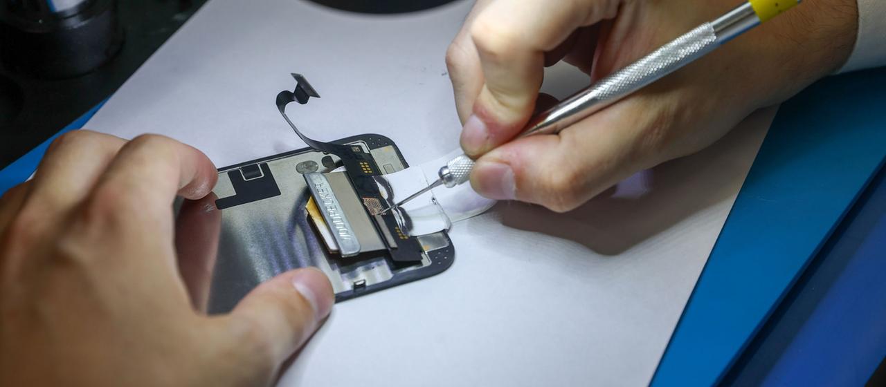 An einem geöffneten Smartphone wird eine Reparatur vorgenommen.