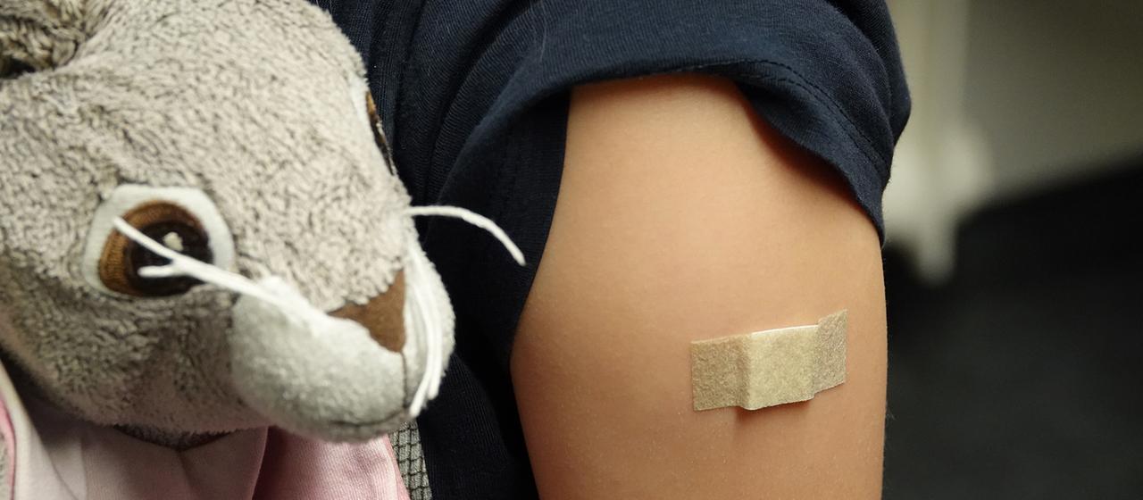 Ein Pflaster klebt auf dem Arm eines Mädchens.