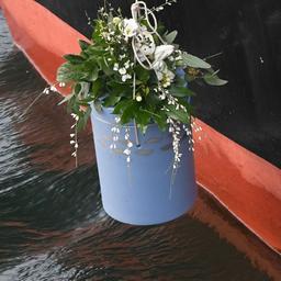 Eine Urne zur Flussbestattung wird ins Wasser gelassen. 