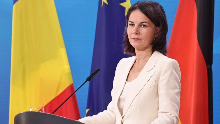 Bundesaußenministerin Baerbock äußert sich vor der Presse, hinter ihr die deutsche Flagge, die der EU und die rumänische.