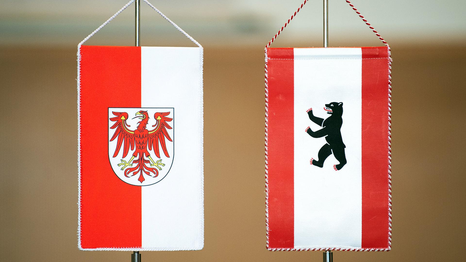 Die Wappen von Berlin und von Brandenburg auf Fähnchen stehen nebeneinander auf einem Tisch (Quelle: picture alliance/dpa/S.Stache) | picture alliance/dpa/S.Stache