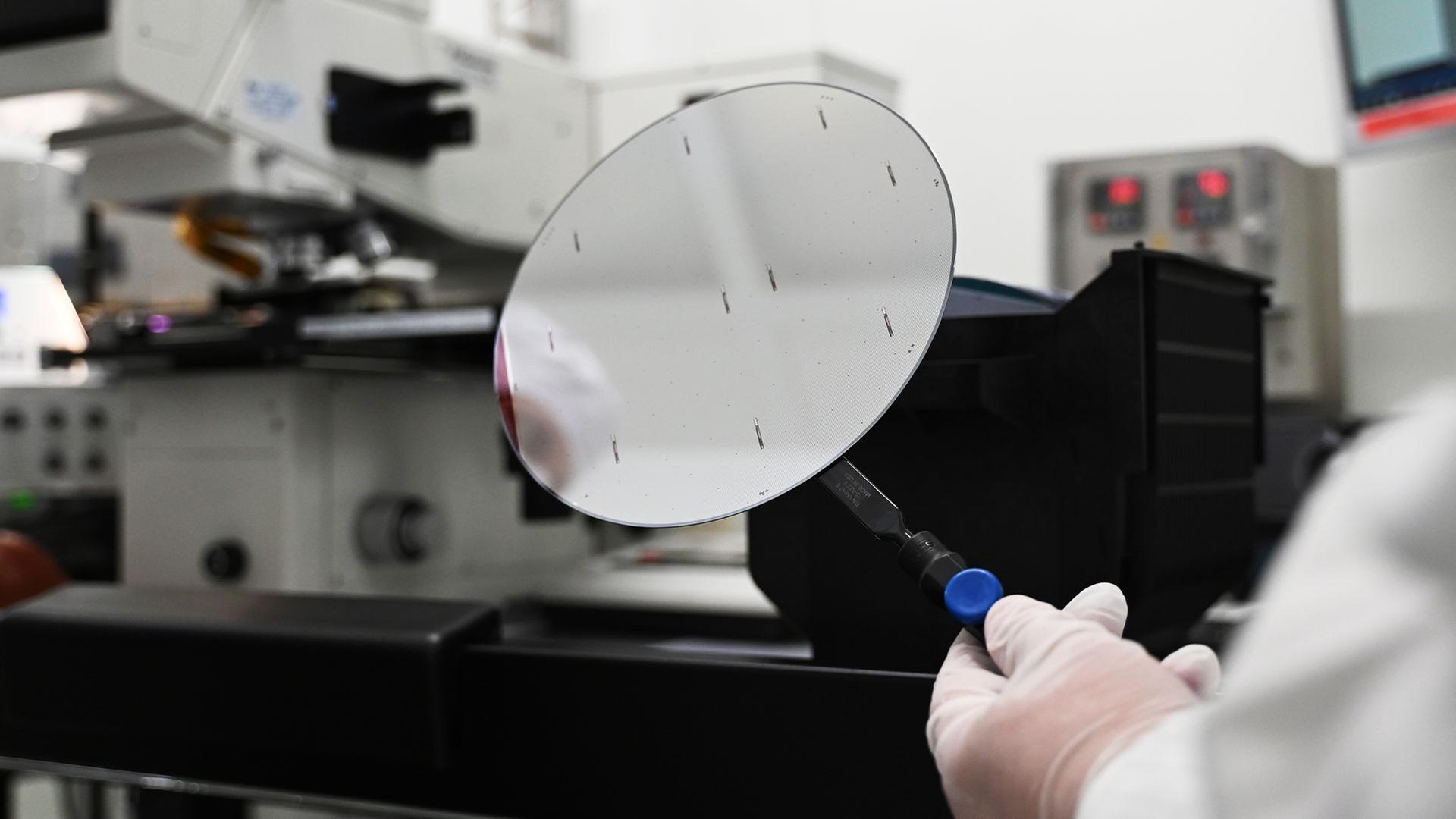 Ein Mitarbeiter der Nexperia Germany GmbH mit einen sogenannten Wafer. | picture alliance/dpa