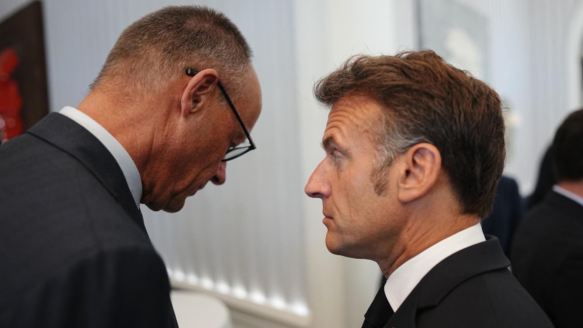 Emmanuel Macron mit hochgezogener Augenbraue, von ihm abgewandt Friedrich Merz | Kay Nietfeld/dpa