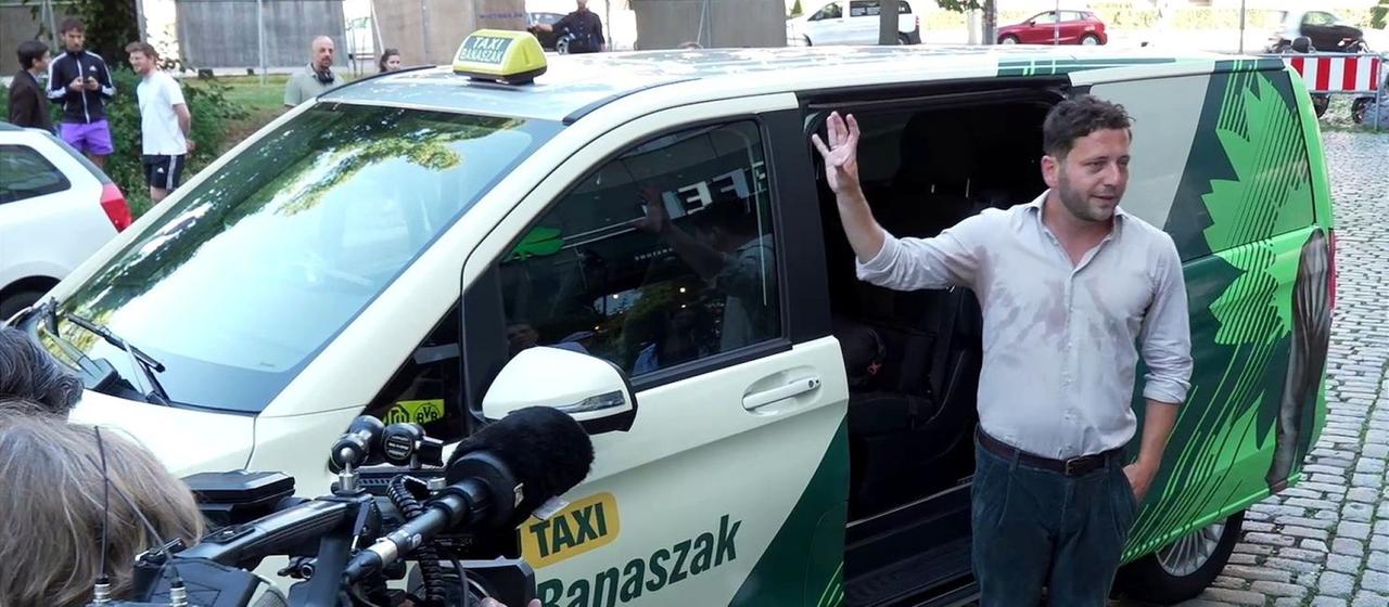 Grünen-Chef Banaszak vor seinem "Taxi Banaszak", mit dem er auch in Sachsen-Anhalt Wahlkampf macht