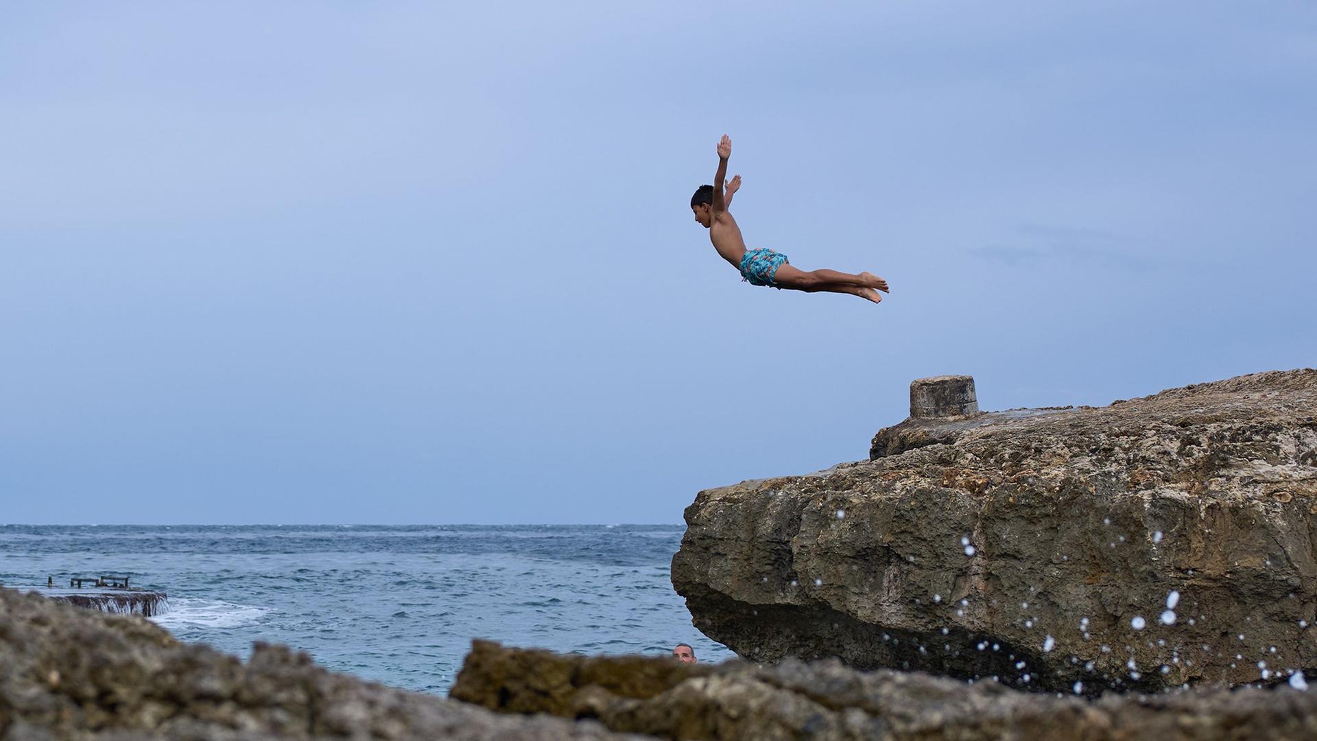 Ein Junge springt von einem Felsen an der KÃ¼ste von Beirut im Libanon. | Hassan Ammar/AP/dpa