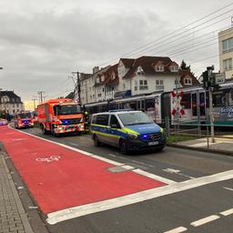 Polizeiautos und orangfarbene Rettungswagen stehen auf der Straße neben einer Straßenbahn und einem Fußgängerübergang.