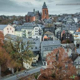 Altstadt mit vielen alten Häusern und der entsprechenden Dachlandschaft aus der Vogelperspektive fotografiert. In der hinteren Mitte ragen ein Dom und ein Baukran hervor.