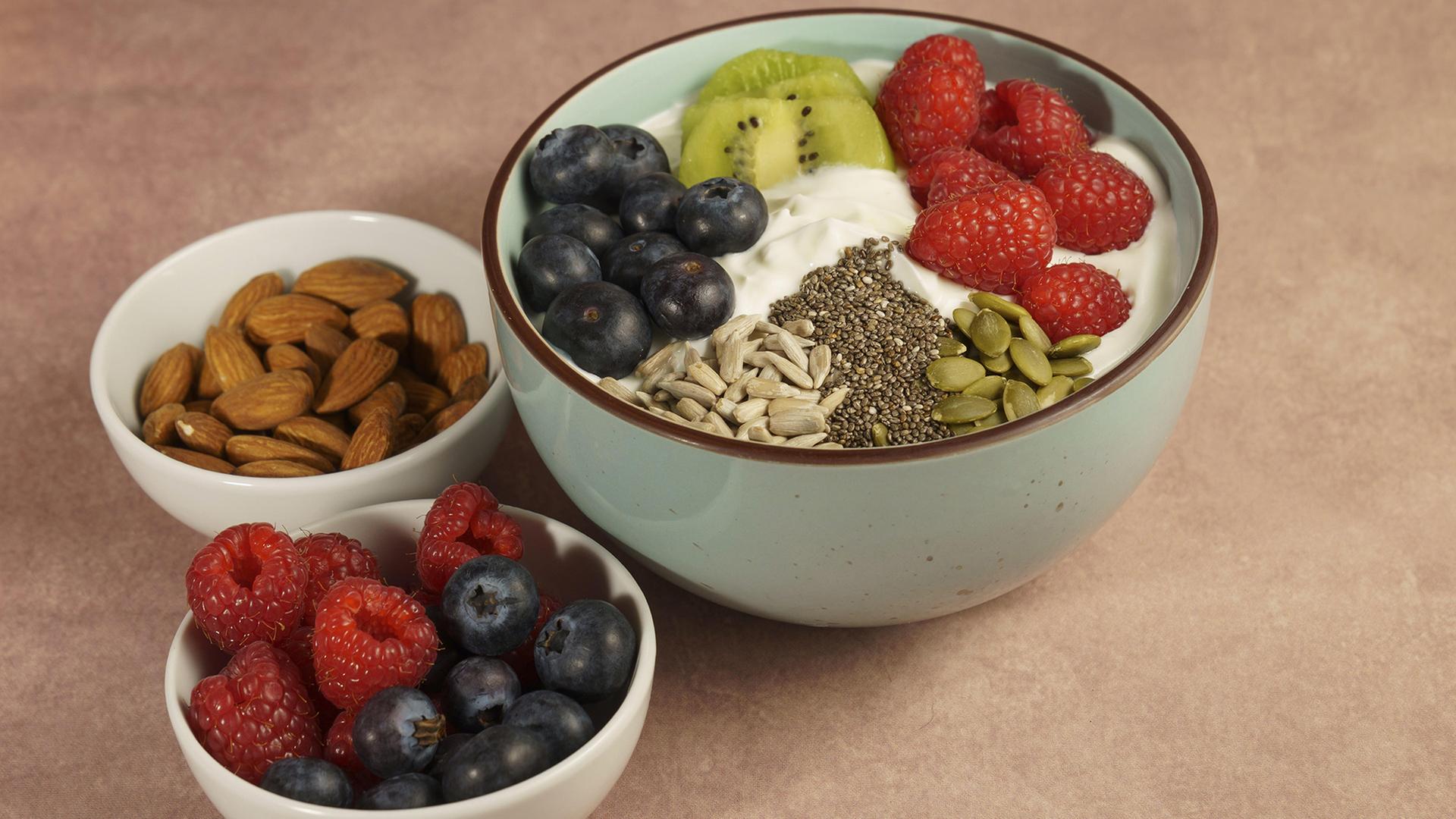 Schalen mit Joghurt, Früchten, Mandeln, Leinsamen, Kürbis- und Sonnenblumenkernen. | picture alliance / imageBROKER