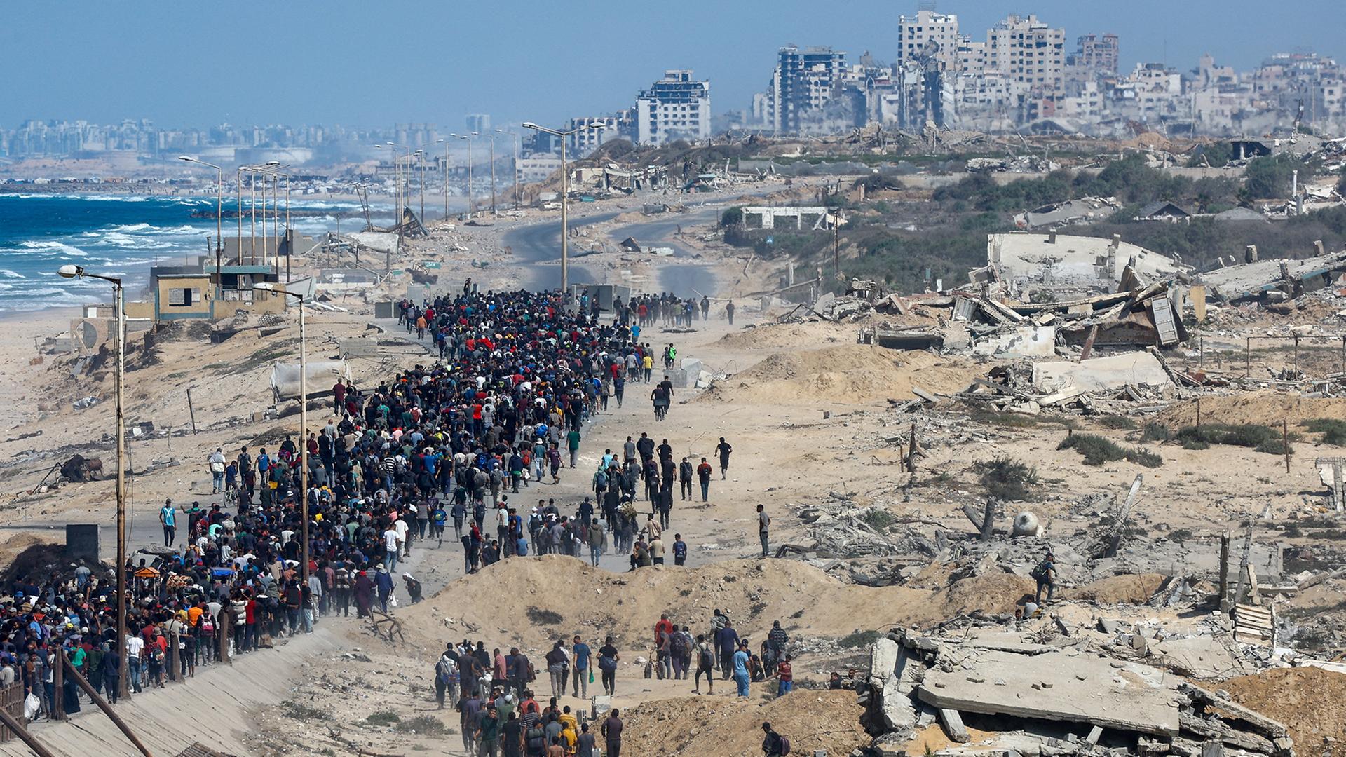 Palästinenser gehen im zentralen Gazastreifen an zerstörten Gebäuden in Richtung Norden. | REUTERS