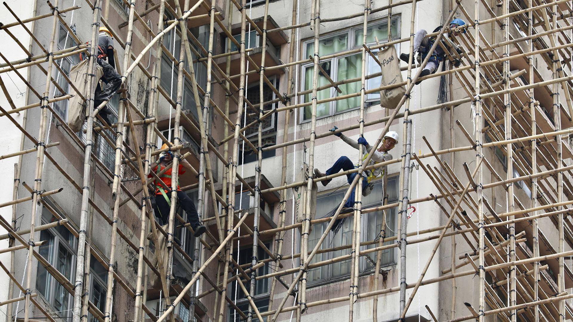 Arbeiter errichten Bambusgerüste für die Instandhaltung von Außenwänden. | dpa