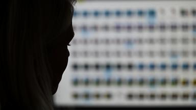 Eine Ermittlerin gegen Kinderpornografie vor einem Monitor mit Fotodateien.