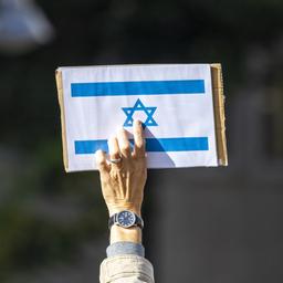 Ein Teilnehmer einer Kundgebung hält ein Schild mit der israelischen Flagge in die Höhe. 