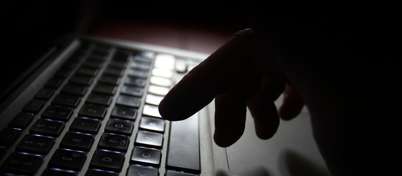 Eine Hand ist über der Tastatur eines Laptops zu sehen.