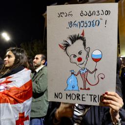 Eine Demonstrantin hält in Tiflis ein Plakat mit einer Karikatur von Geschäftsmann Iwanischwili, der hinter der Regierungspartei "Georgischer Traum" steht.