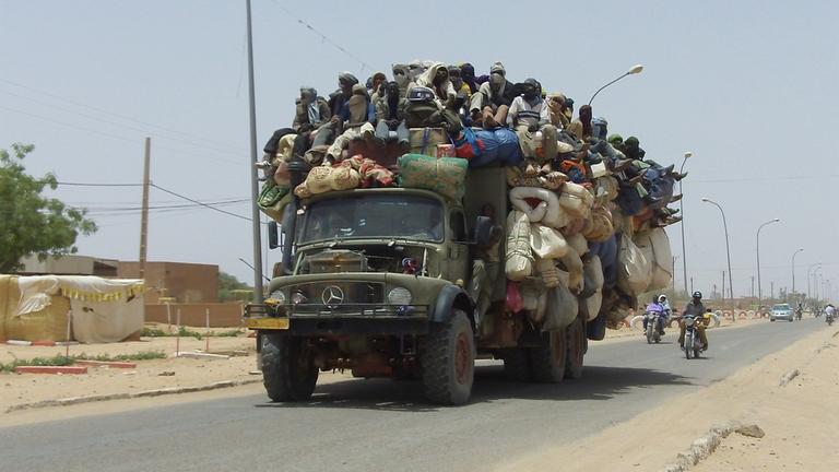 Lkw, auf dessen Ladefläche viel Gepäck gestapelt wurde und oben drauf Menschen sitzen (Archivbild: 2015)