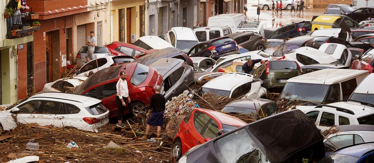 Anwohner betrachten aufgestapelte Autos, die von den Überschwemmungen in Valencia weggeschwemmt wurden. (Archivbild: 30.10.2024)