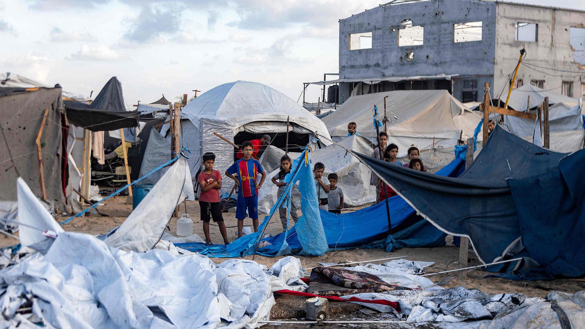 Kinder stehen in einem zerstörten Teil eines Zeltlagers in Gaza | AFP