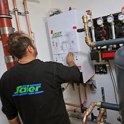 Heizungsbauer nimmt nach Einbau einer Waermepumpe Einstellungen vor.