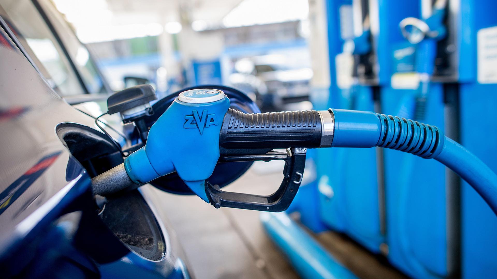 Eine Zapfpistole steckt an einer Tankstelle in der Tanköffnung eines Fahrzeugs | Hauke-Christian Dittrich/dpa