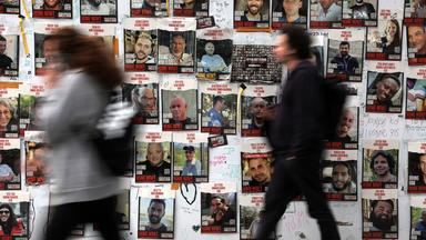Personen gehen an Plakaten mit Bildern von den israelischen Geiseln, die von der Hamas festgehalten werden, vorbei.