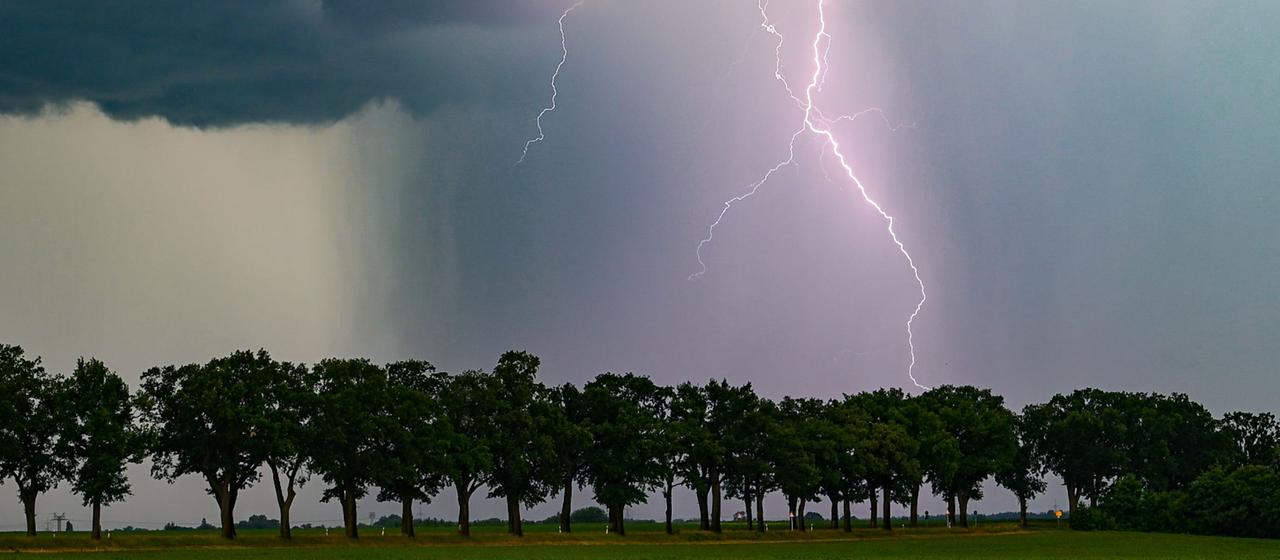 Ein Blitz leuchtet am späten Abend über der Landschaft. 