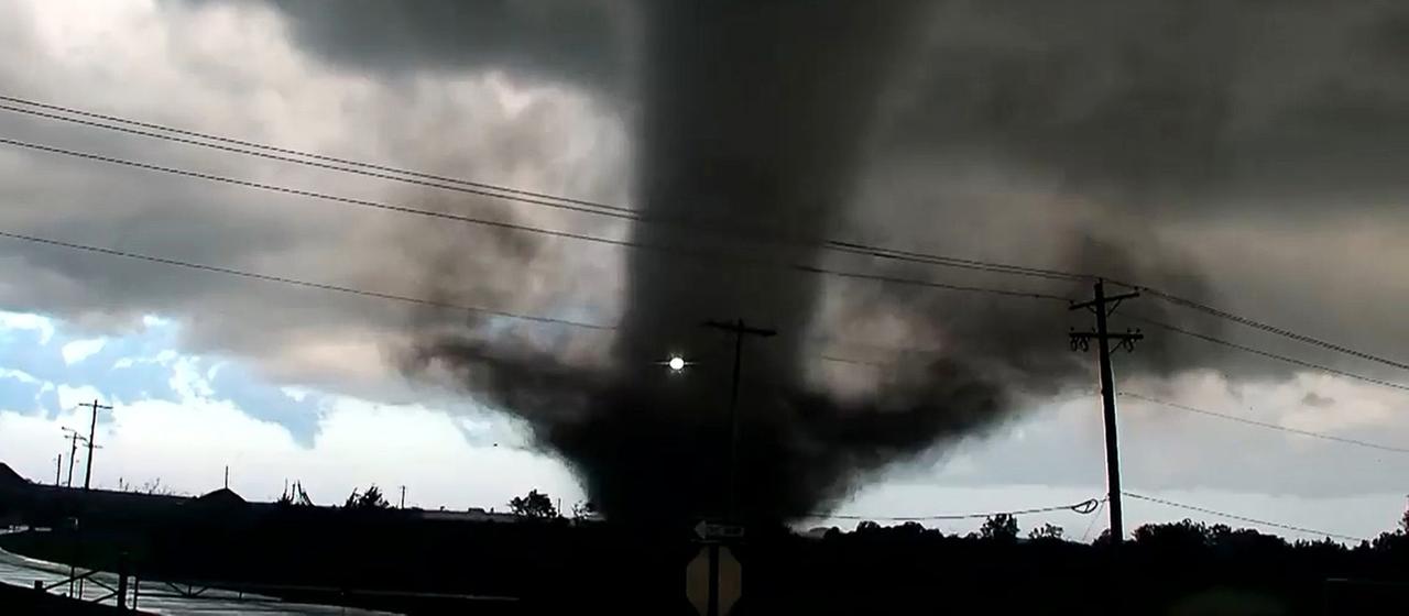Über einem Highway ist ein dunkler Tornado zu sehen.