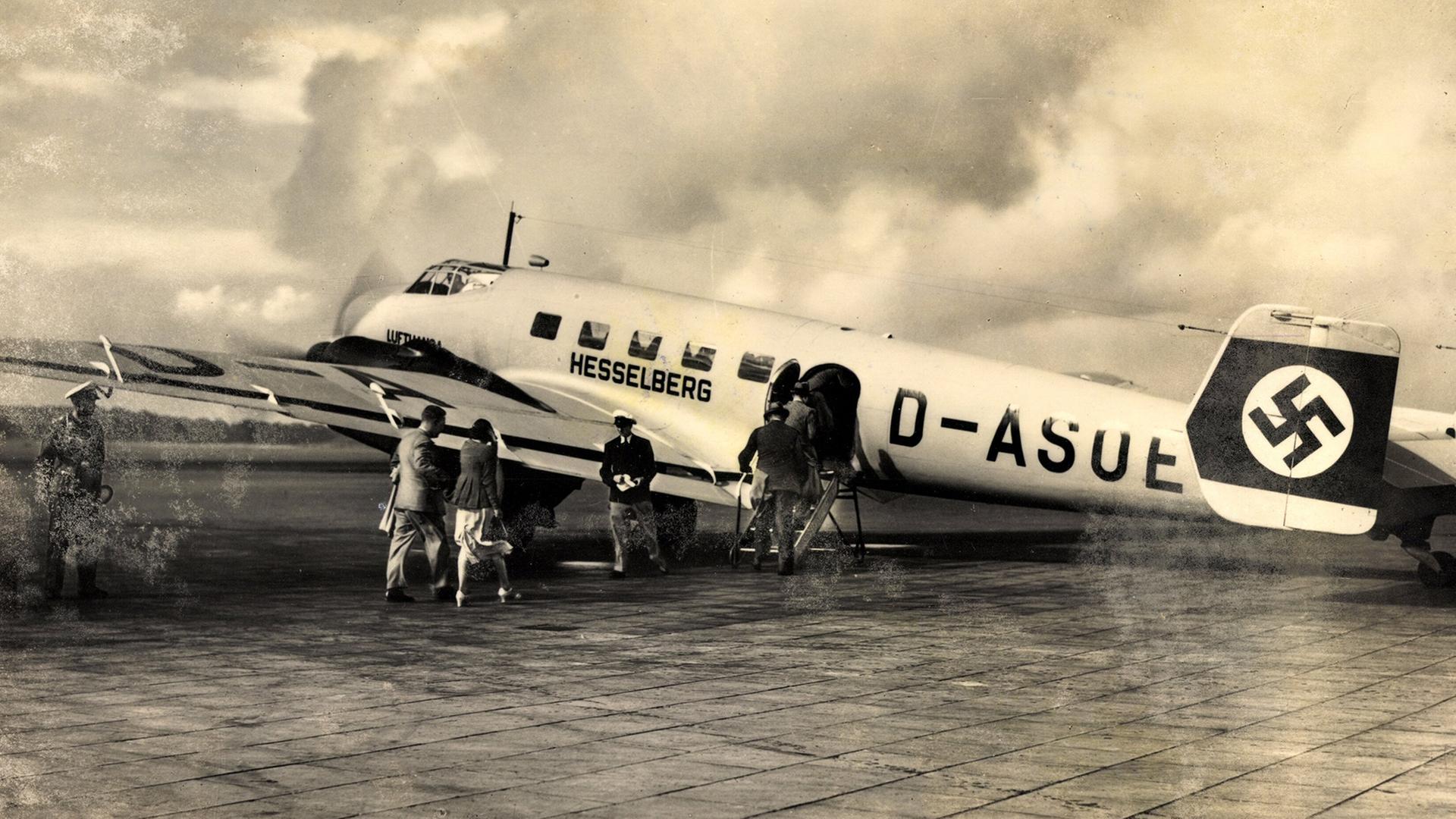 Menschen besteigen ein historisches Flugzeug das auf einem Rollfeld steht. | picture alliance / arkivi