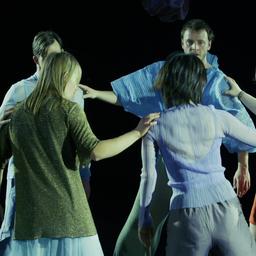 Tanzszene mit acht Personen im Kreis auf einer Theaterbühne