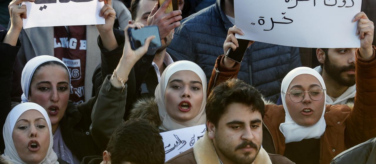 Frauen skandieren in Damaskus Slogans, während sie Plakate mit arabischen Aufschriften halten