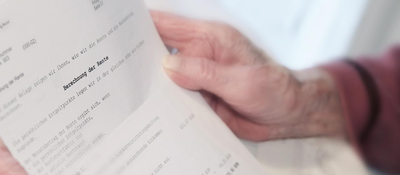 Eine Frau hält einen Rentenbescheid in den Händen.