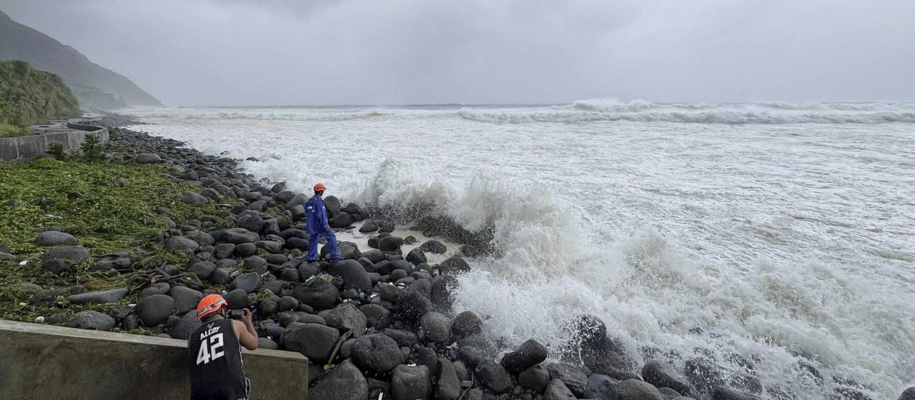 Menschen beobachten, wie starke Wellen auf Basco in der Provinz Batanes im Norden der Philippinen einschlagen.