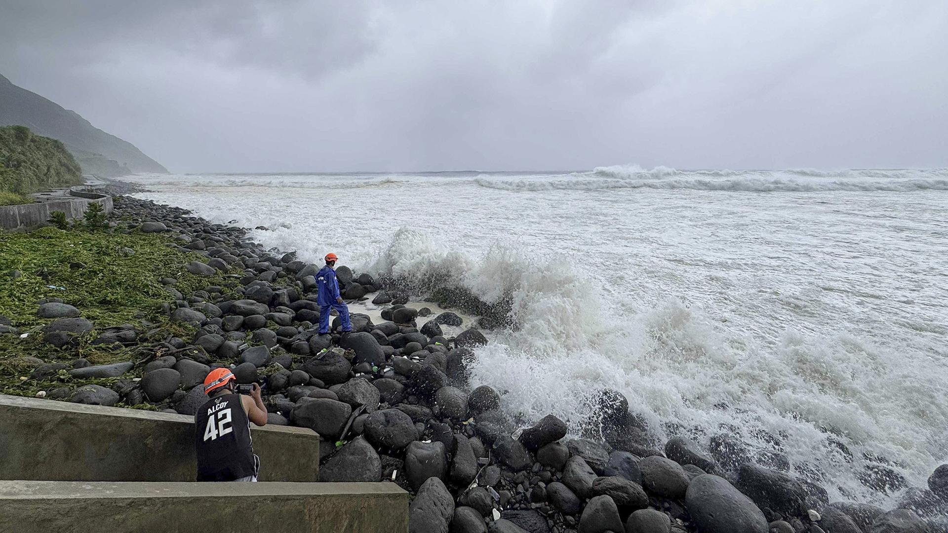 Menschen beobachten, wie starke Wellen auf Basco in der Provinz Batanes im Norden der Philippinen einschlagen. | dpa
