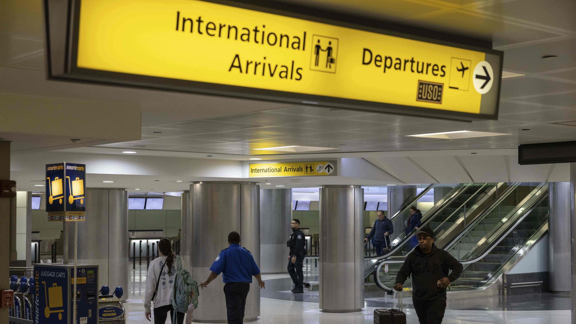 Menschen mit Koffern gehen durch das internationale Terminal des Newark Liberty International Airport. | dpa
