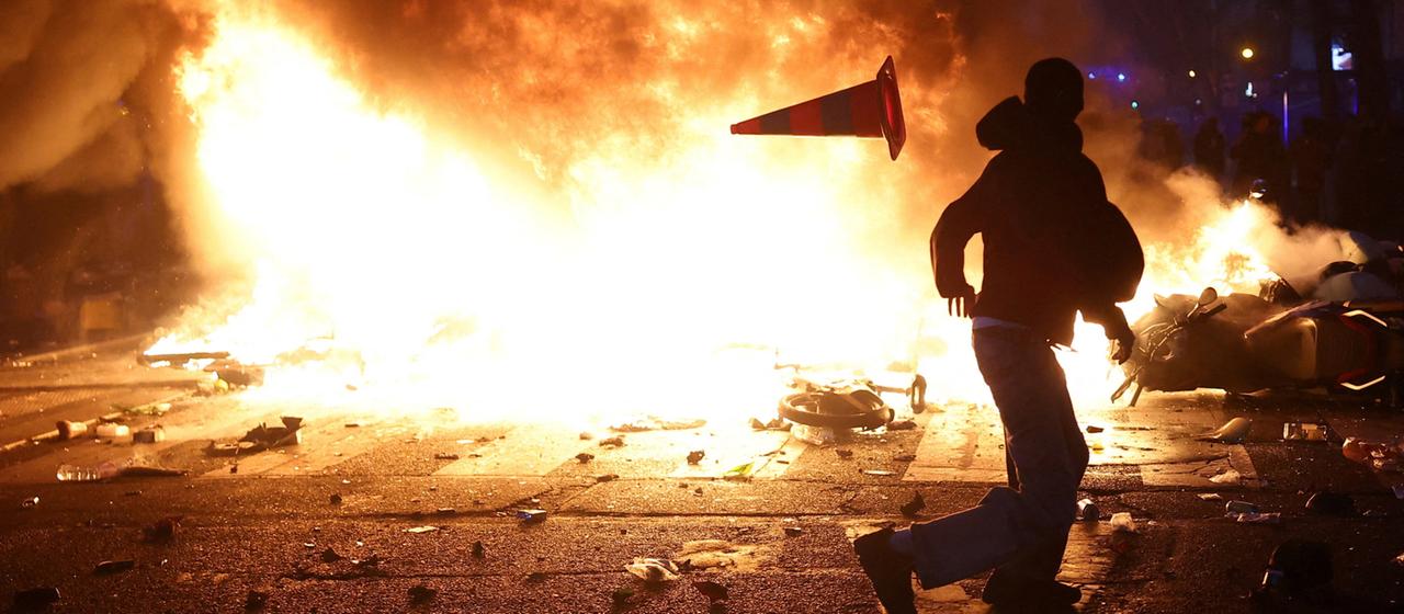 Ein Demonstrant steht vor brennenden Barrikaden in der französischen Hauptstadt Paris.