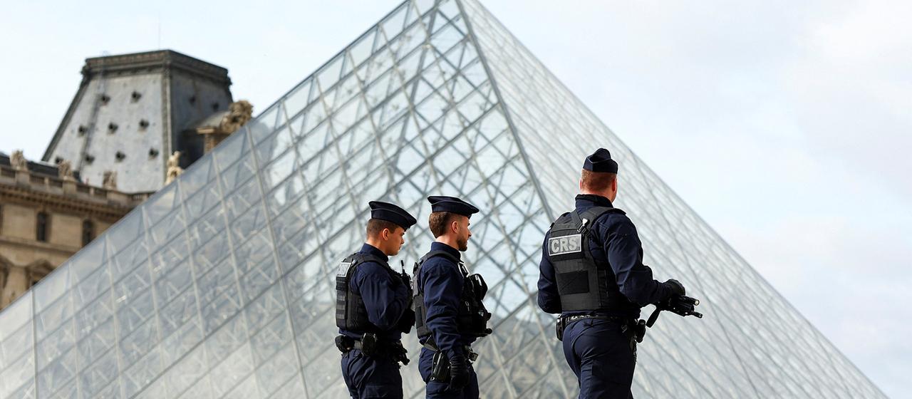 Drei Polizisten in der Nähe der Glaspyramide des Louvre-Museums