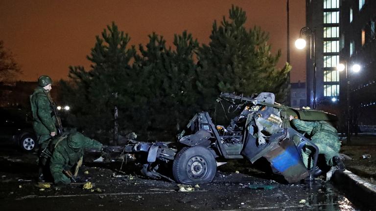 Inspekteure begutachten ein explodiertes Auto in Donezk.