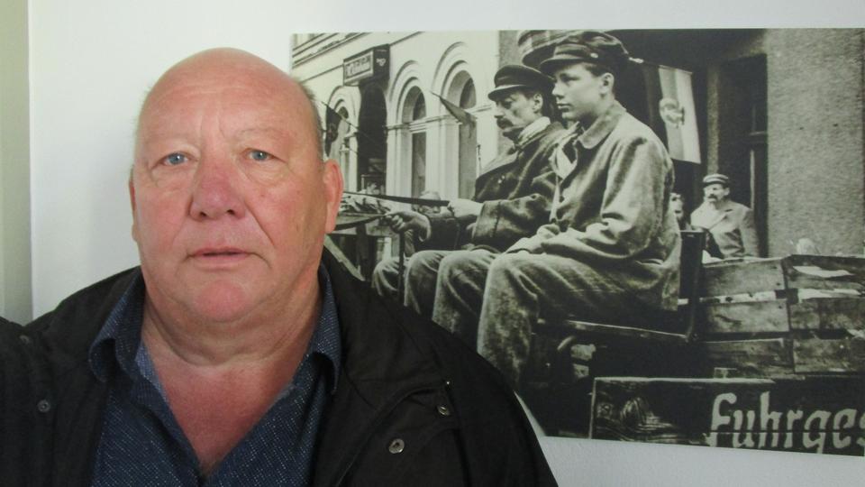 Michael Kröger steht vor einem Schwarz-Weiß-Foto, das an einer Wand hängt