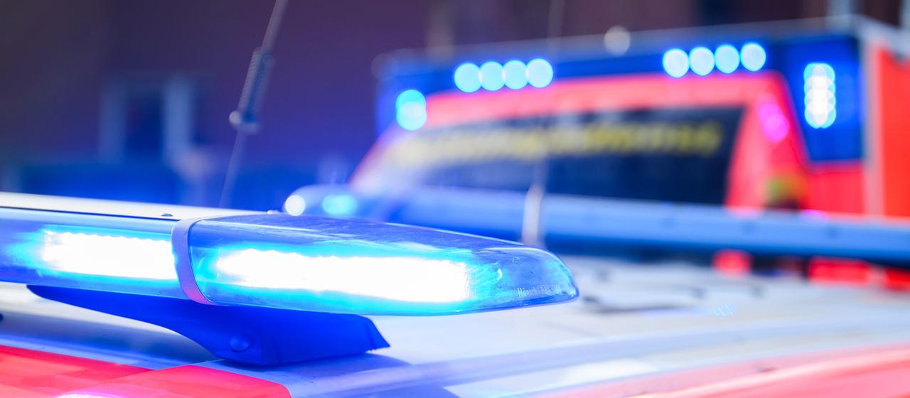 Blue lights shine on an emergency vehicle and an ambulance at an emergency scene.