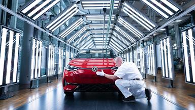 Ein Mitarbeiter von Volkswagen inspiziert  im Lichttunnel  einen VW ID.3.