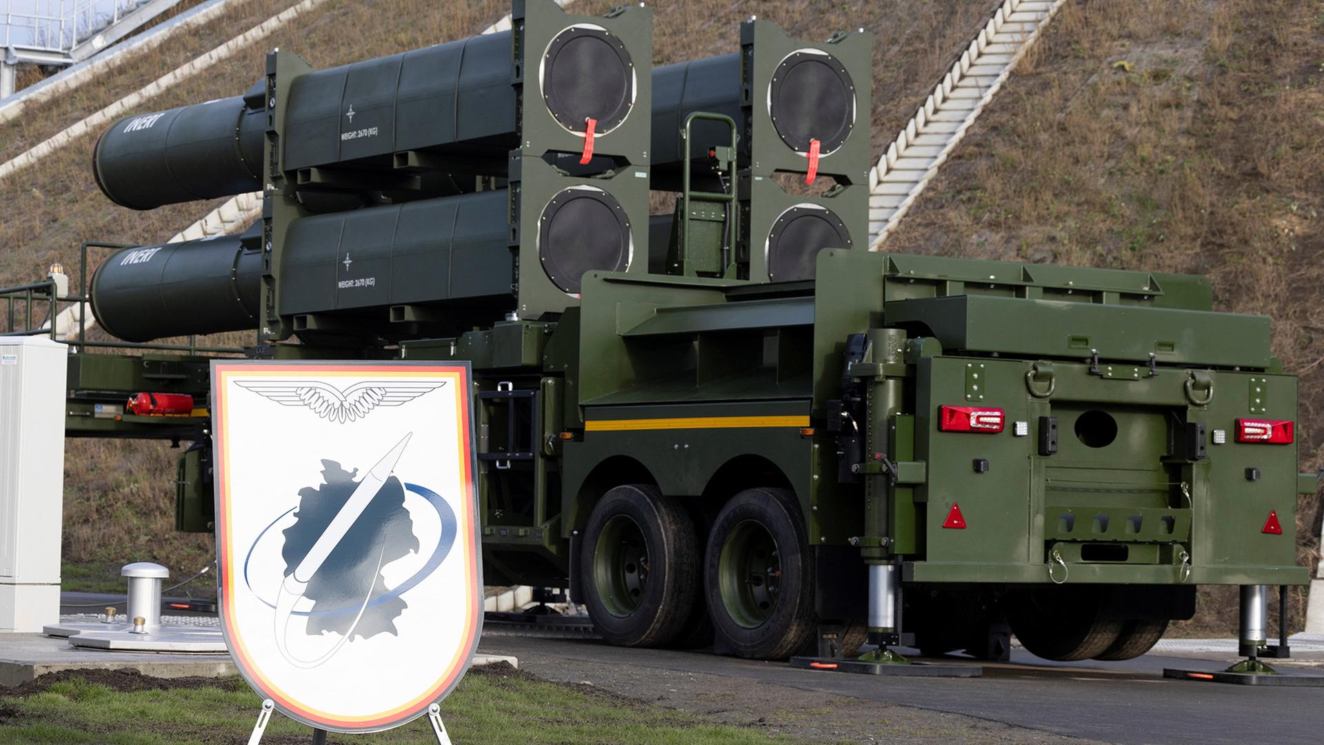 Ein Schild, das die Bundesrepublik Deutschland zeigt, steht neben militärischem Gerät. | REUTERS